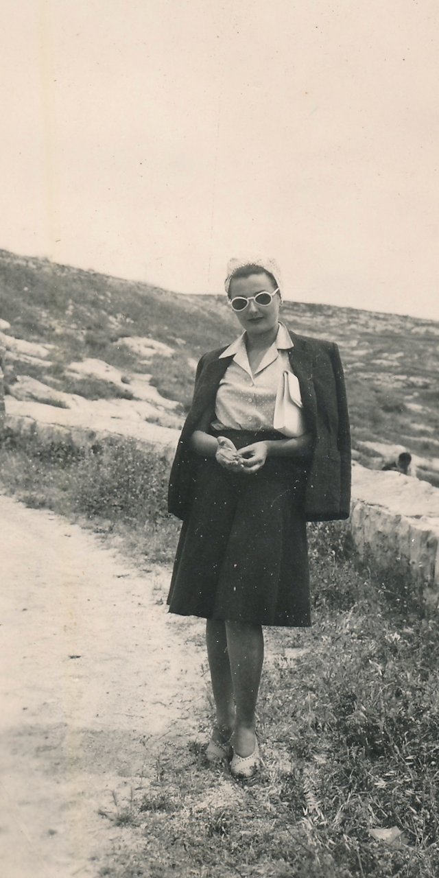 Vintage woman in sunglasses posing outdoors in stylish 1950s attire.